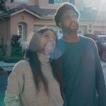A couple joyfully standing in front of their new home, symbolizing new beginnings and home ownership.