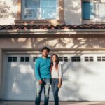 A joyful couple stands in front of their newly purchased home, symbolizing togetherness and success.